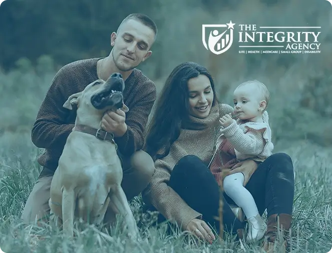 Man and woman with young baby daughter and dog sitting in a field