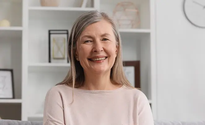 Elderly woman smiling at camera in home office setting