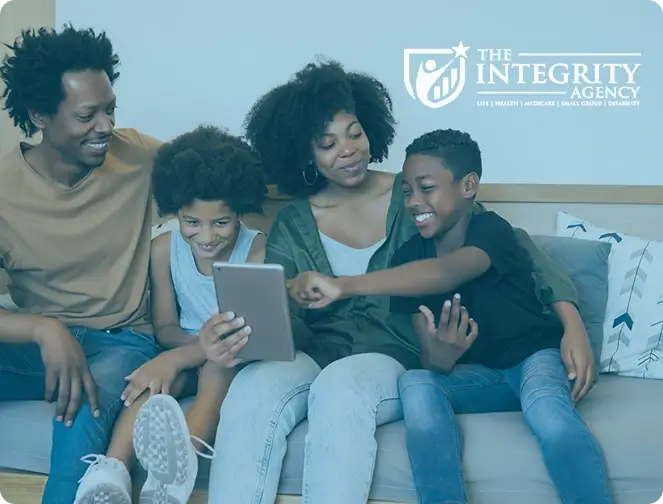 Black mother and father sitting on the couch with two young sons smiling and looking at a tablet